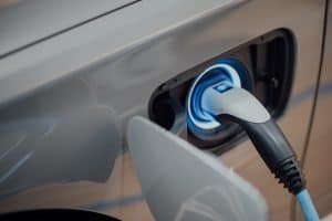 Veículo elétrico em carregamento, ilustrando exportação temporária para reparo de bateria e reimportação em garantia