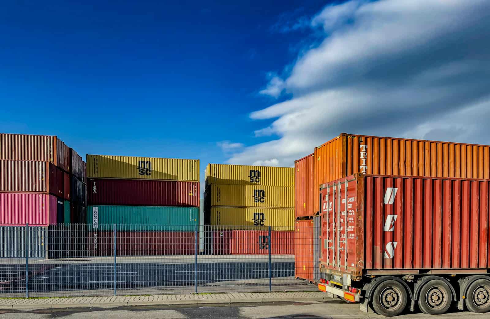 Caminhão em frente a contêineres: importação por conta e ordem para empresas de Minas Gerais